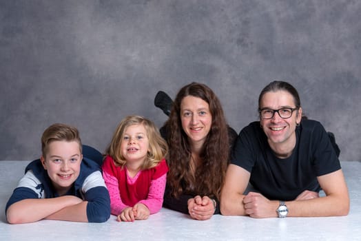 nice family lying on the flor in front of gray background