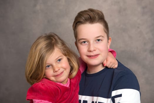 brother and sister together in front of gray background