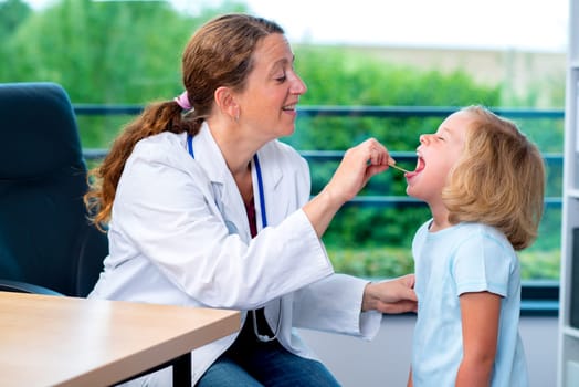 female pediatrician in white lab coat examined little girl