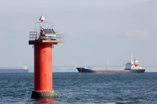 lighthouse with cargo ship in the sea