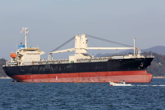 large cargo ship and fishing boat against blue sky