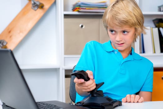 blond boy is playing computer game in his room