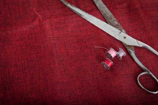 a red cloth with scissors and thread for sewing