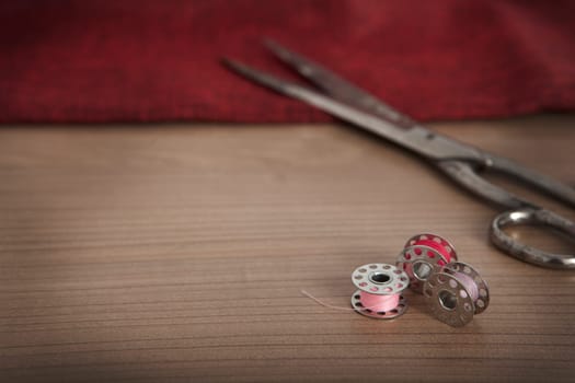 a red cloth with scissors and thread for sewing