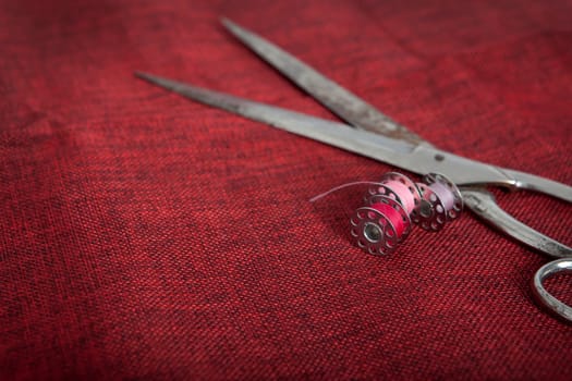 a red cloth with scissors and thread for sewing