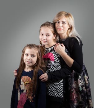 Portrait of a beautiful mother with her 2 daughters, studio shot.