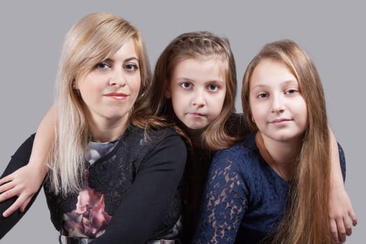 Portrait of a beautiful mother with her 2 daughters, studio shot.