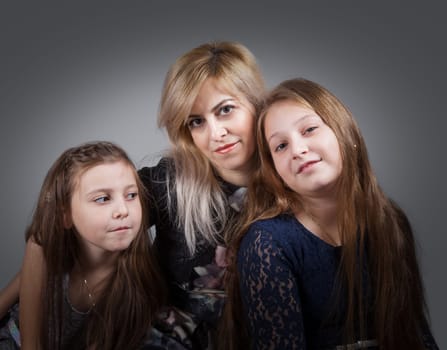 Portrait of a beautiful mother with her 2 daughters, studio shot.