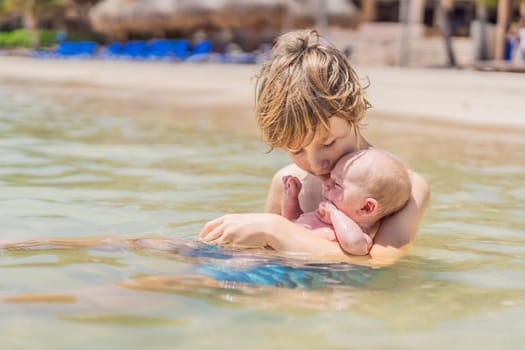 An older brother gently holds his baby sibling while swimming in the sea, sharing a joyful and heartwarming moment of family bonding and summer fun in the water. A perfect blend of love, care, and childhood adventure.