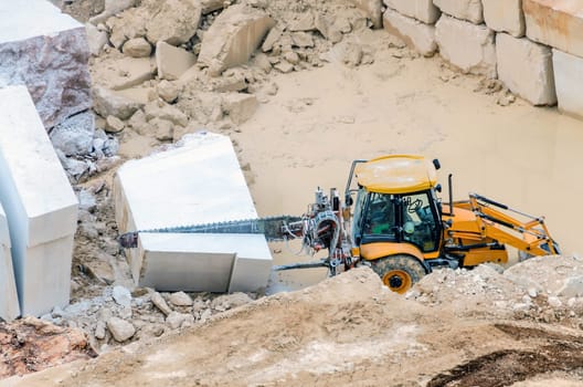 Industrial marble quarry, with cut blocks and workers and machines bulldozer at work.