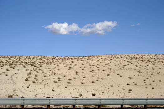 A single cloud over the sand-shaped hills of the desert at Yucca Valley.