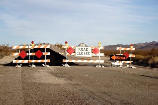 A road barrier with signal lights and a pile of tar on Route 66.