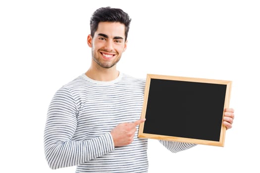 Handsome young man holding and pointing to a small chalkboard, isolated over a white background
