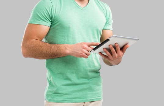 Handsome young man showing something on a tablet, isolated over gray background