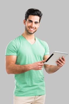 Handsome young man showing something on a tablet, isolated over gray background