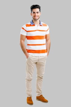 Full length portrait of happy handsome young man isolated over a gray background