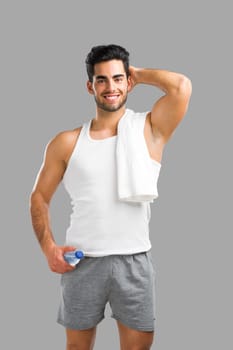 Portrait of a athletic young man holding a water bottle, isolated over a gray background