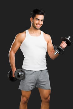 Portrait of handsome young man lifting weights, isolated over a gray background