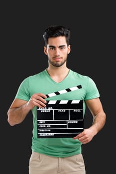Portrait of handsome young man holding a clapboard, isolated on gray background