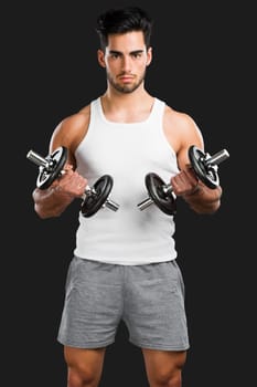 Portrait of handsome young man lifting weights, isolated over a gray background