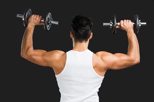 Portrait of handsome young man lifting weights, isolated over a gray background