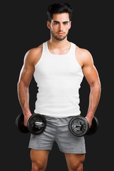 Portrait of handsome young man lifting weights, isolated over a gray background