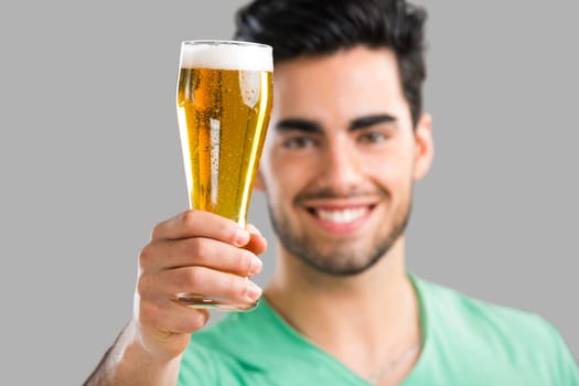 Portrait of handsome young man tasting a draft beer, isolated on gray background