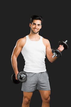 Portrait of handsome young man lifting weights, isolated over a gray background