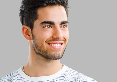 Portrait of handsome young man smiling, isolated on gray background