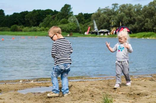 Boy and girl playing in the sand on the shore of Lake