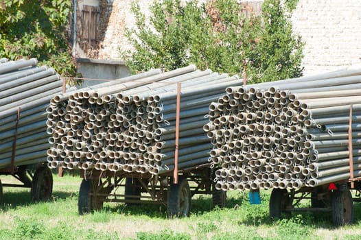 Farm wagons loaded with metal rigid pipes for irrigation