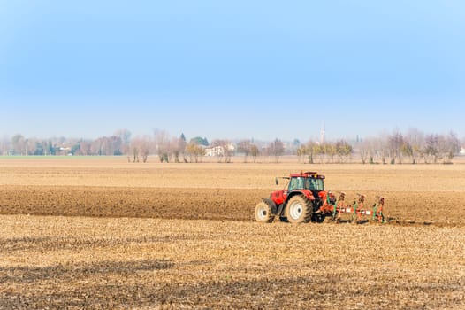 Agricultural labor, Red Tractor plowing a field