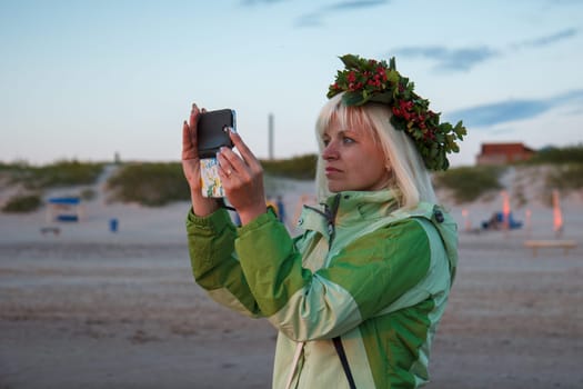 Blond female taking a picture with a phone at the beach