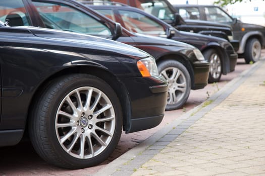 A line of parked cars by the street sidewalk