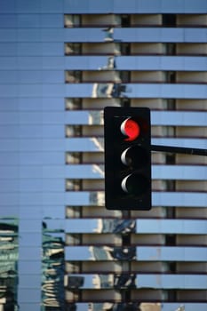 A red light stands in front of a modern multi-storey high-rise.