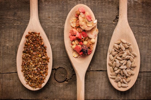 Three wooden spoon with muesli and flax seed and sunflower seed