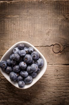 Fresh blueberries in a white bowl on an old rustic table