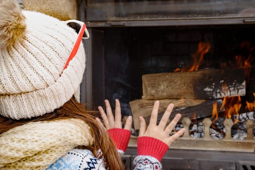 Winter at home, a pretty young girl sitting near the fire place