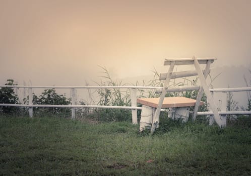 White bench in foggy morning on the mountain. Retro or vintage filtered image.