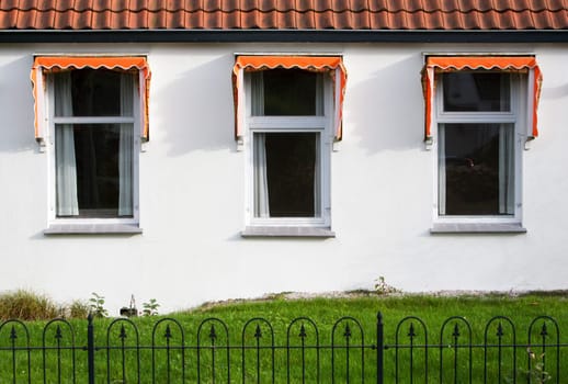 Three windows with orange awnings, a small garden and roof tiles. A typical dutch house.