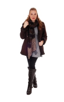A lovely blond young woman standing in a winter jacket and boots with a.big scarf, isolated for white background..
