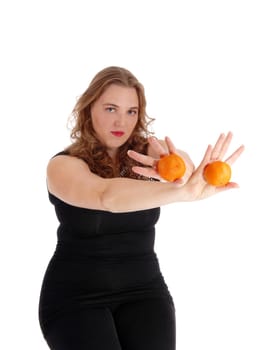A young blond woman in black sweater and tights holding two oranges in.her outstretched arms, isolated for white background..