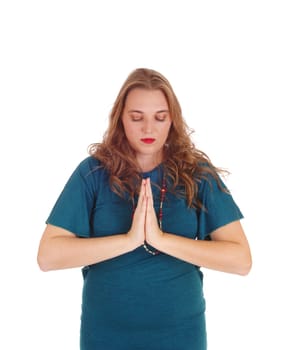 A pretty woman with her hands folded standing isolated for white.background praying with her eye's closed..