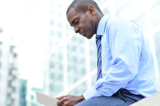 Businessman using his PC tablet while sitting on a bench