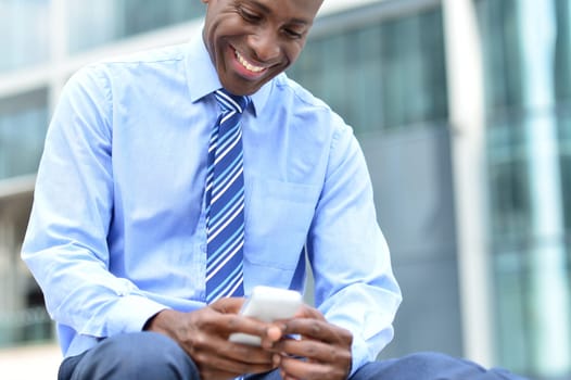 Smiling male entrepreneur looking at his cell phone