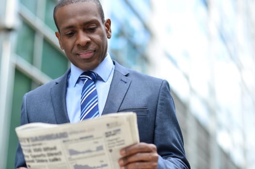 Middle aged business man reading newspaper seriously