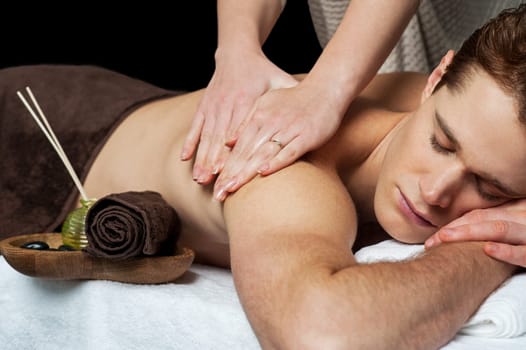 Young man getting massage at a spa saloon