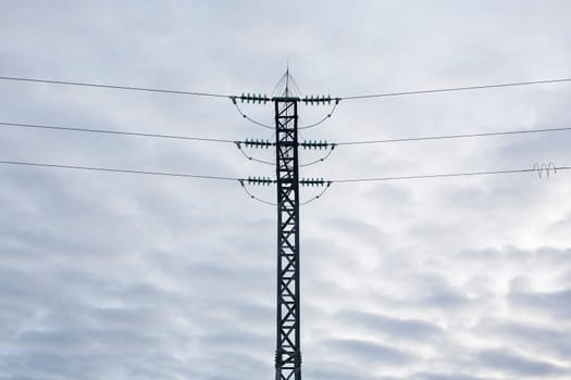 High-voltage steel lattice tower over cloudy blue sky