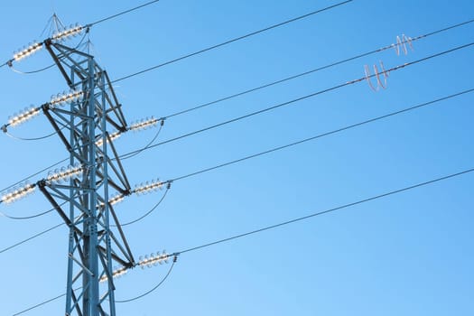 High voltage power pylons against blue sky. Low view