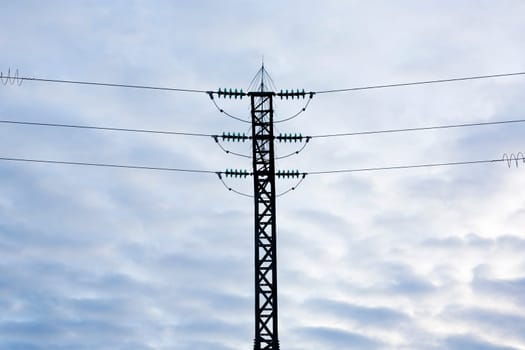 High-voltage steel lattice tower over cloudy blue sky